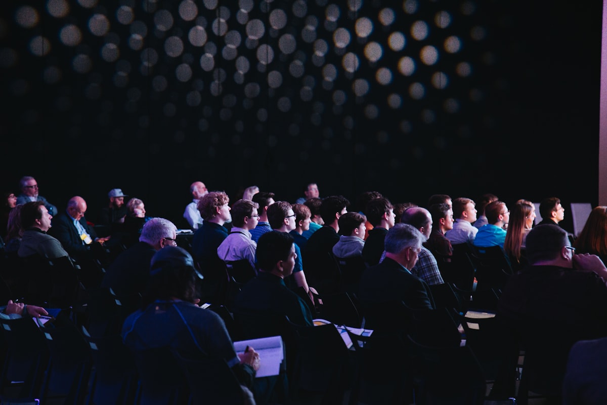Audience at a corporate announcement in a darkened conference hall